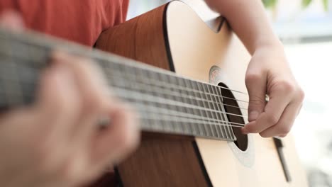 primer plano de manos tocando una guitarra acústica