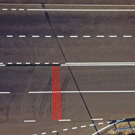 few long vertical red stripes painted on one side of the road surface and cars passing. aerial view of wide asphalt road divided into two opposite sides for cars. camera moves right