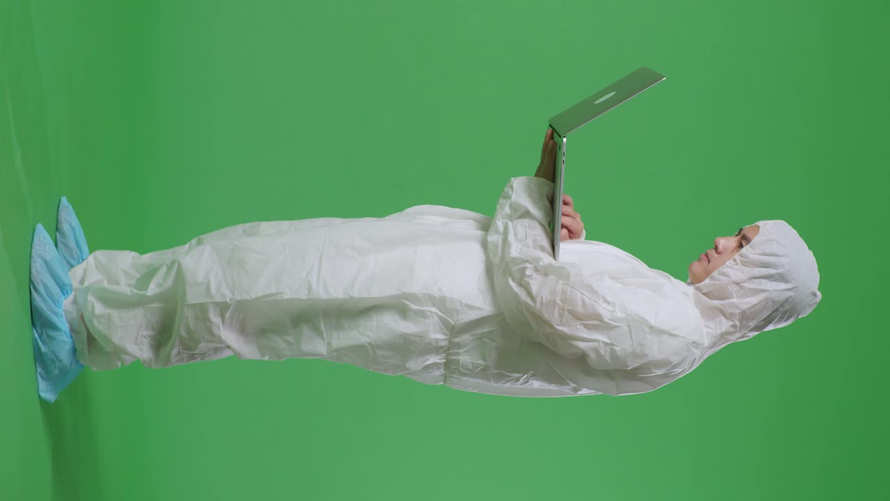 녹색 스크린 배경에 노트북으로 타이핑하는 아시아 남성 과학자의 전체 몸의 측면 시각