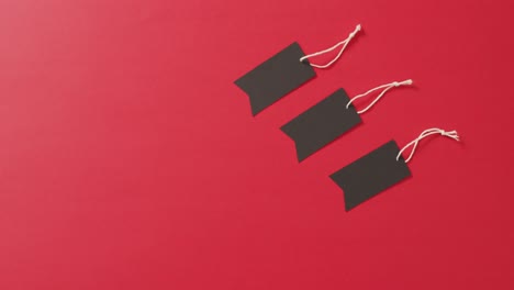 Three-black-sale-tags-with-with-string-on-red-background-with-copy-space
