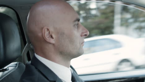 side view of middle aged bold man wearing suit and driving car