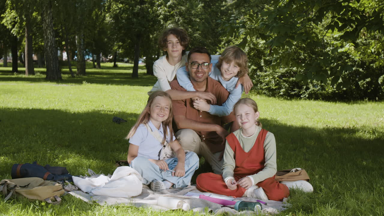 Happy group of children and a teacher posing in a park
