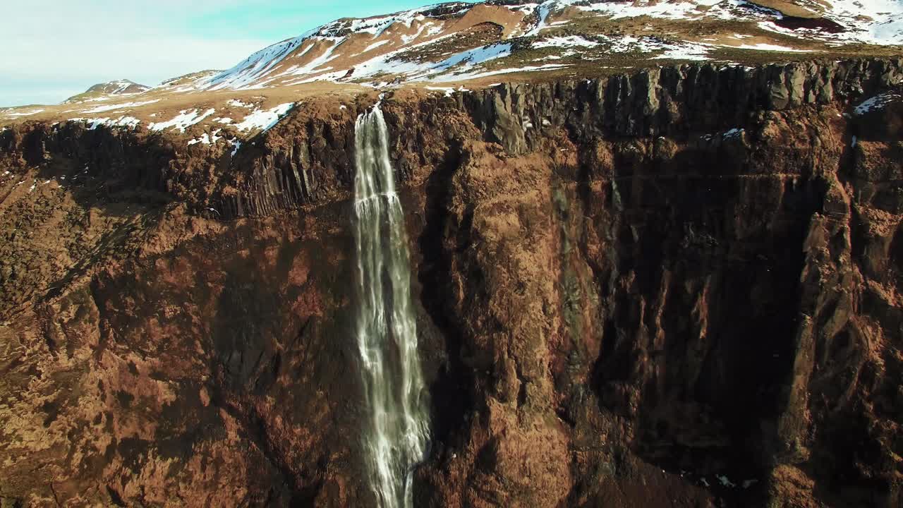 toma aérea de una empinada cascada con gaviotas volando junto a la montaña en un día soleado