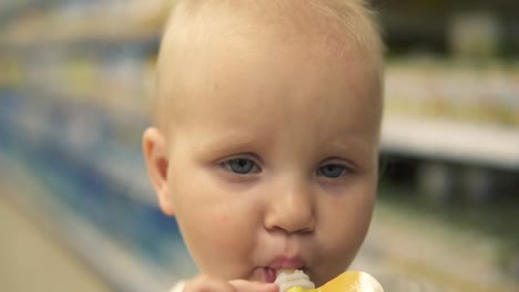 little baby drinks juice from a plastic bottle sitting in the supermarket cart. thirsty little child shopping with family