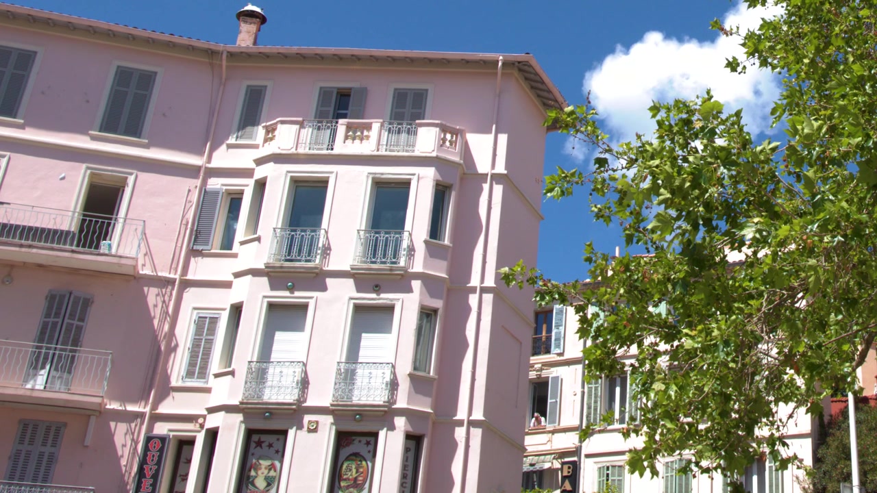 Inquadratura statica dal basso di un palazzo europeo rosa sotto un cielo azzurro limpido.