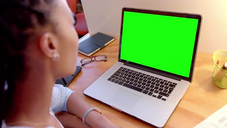 African-american-casual-businesswoman-at-desk-watching-laptop-with-green-screen,-slow-motion