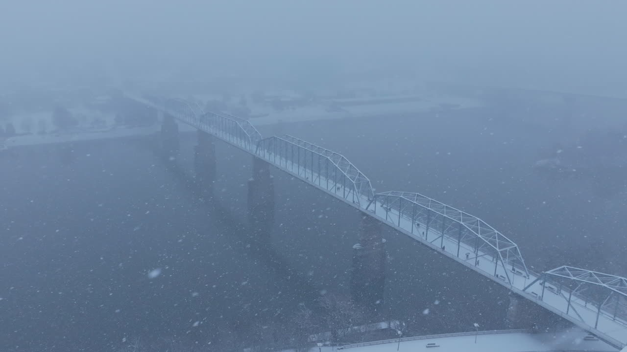 Aerial drone footage during a snowstorm flying around a walking bridge in Chattanooga, TN.