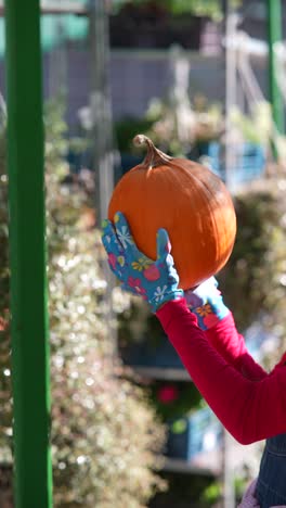 mujer sosteniendo una calabaza en un jardín