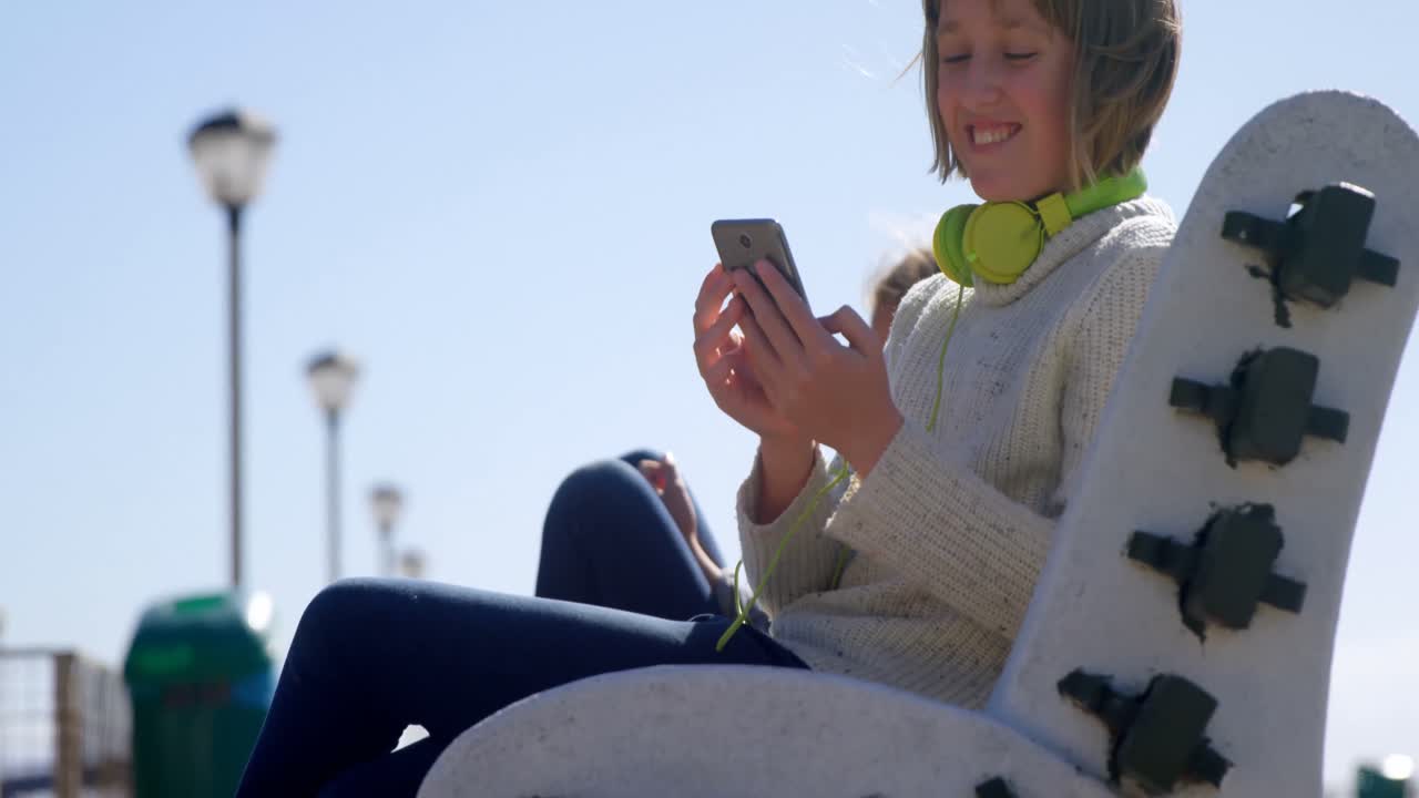 Teenage girl using mobile phone at beach 4k