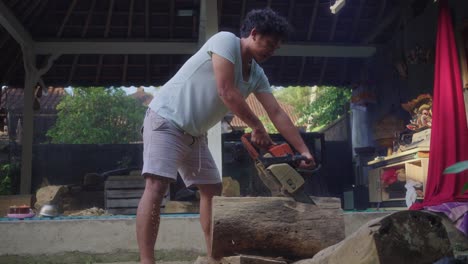 balinese wood carver cutting woods using chainsaw