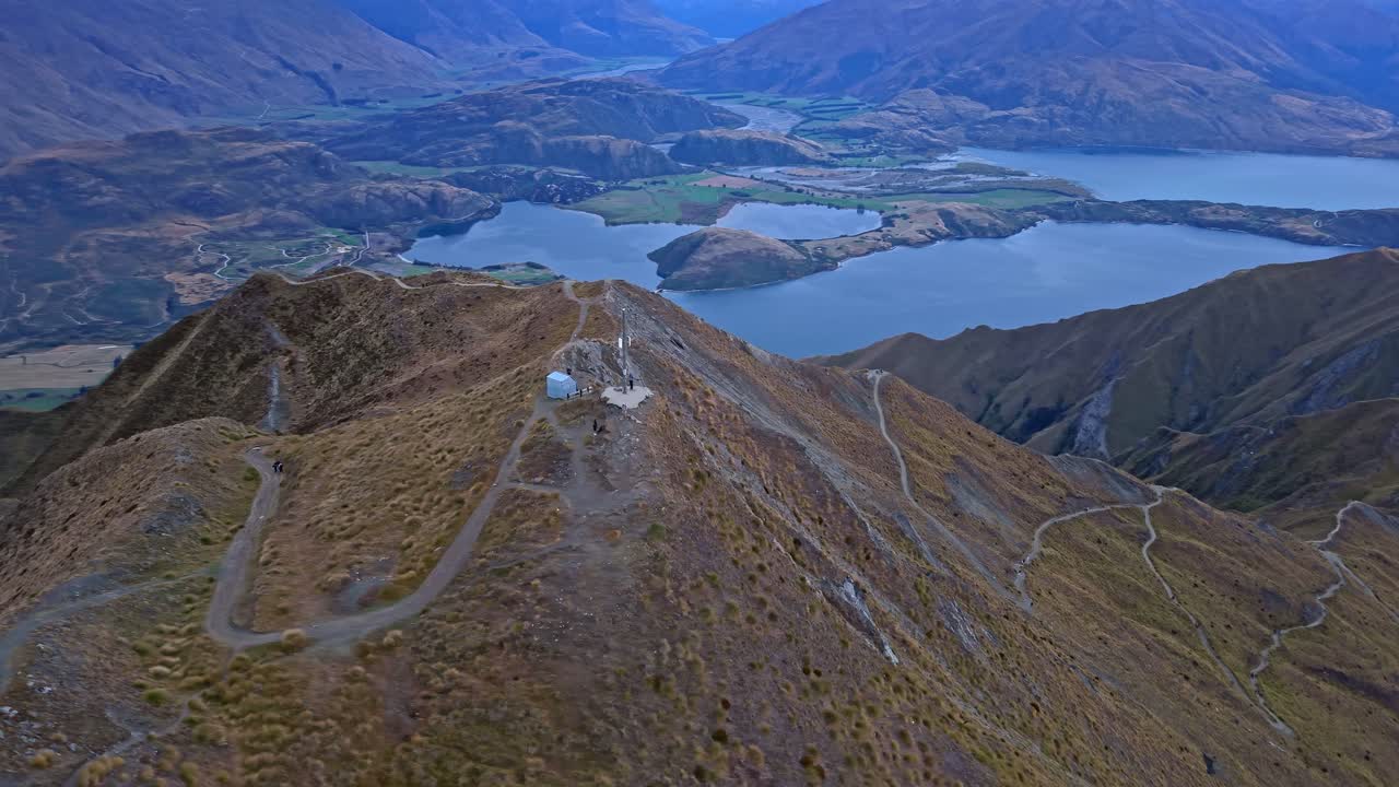 Drone orbits Roys Peak summit shelter overlooking Lake Wanaka and ridgelines