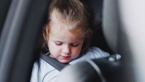 Young-Girl-Watching-Digital-Tablet-In-Back-Seat-On-Car-Journey