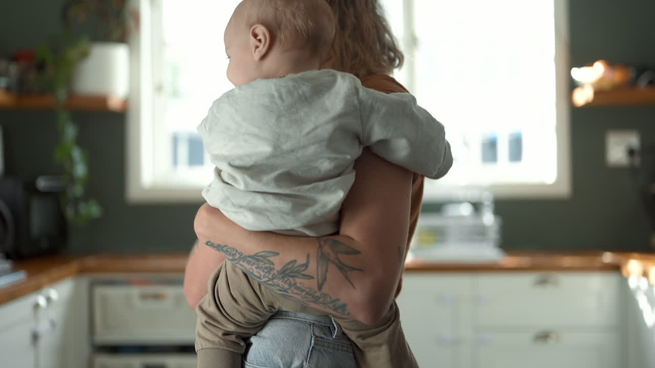 Mamma che tiene in braccio il bambino in cucina