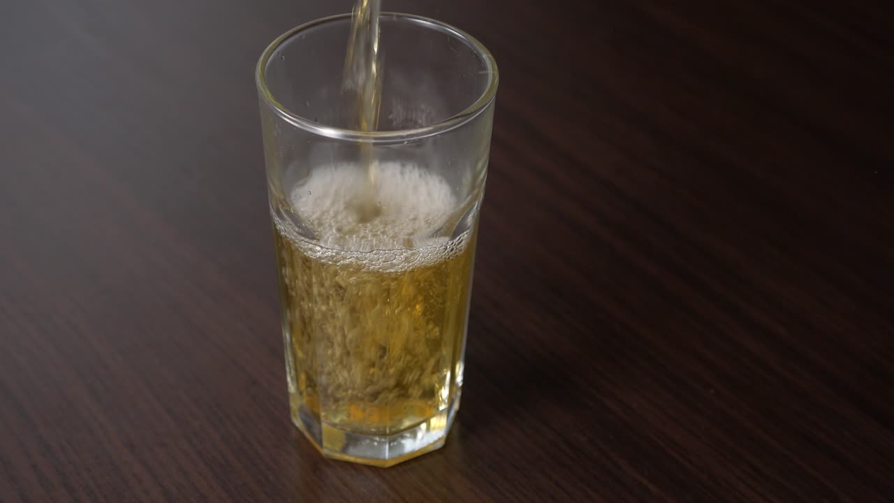 verter jugo de manzana en un vaso alto sobre una mesa de madera