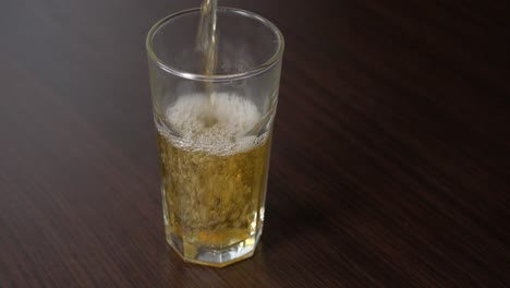 pouring apple juice into tall glass on a wooden table