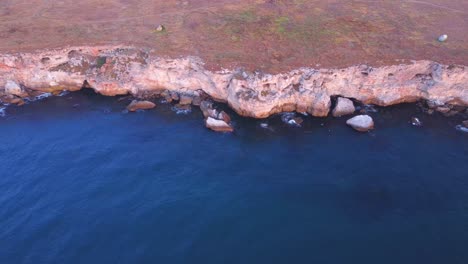 Vista-Aérea-De-Arriba-Hacia-Abajo-De-Las-Olas-Salpicadas-Contra-La-Costa-Rocosa,-Fondo