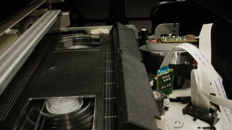 old video recorder inside close-up, vhs. retro player in neon blue light, vintage video cassette broadcasting, audio tape.