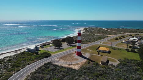 red and white striped lighthouse next to clear turquoise ocean