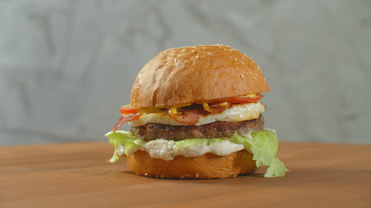 yummy concepto de comida rápida. hamburguesa fresca a la parrilla casera con carne patata tomates pepino lechuga cebolla y semillas de sésamo. estilo de vida no saludable. fondo de la comida.