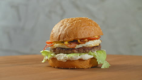 Yummy-fast-food-concept.-Fresh-homemade-grilled-burger-with-meat-patty-tomatoes-cucumber-lettuce-onion-and-sesame-seeds.-Unhealthy-lifestyle.-Food-background.