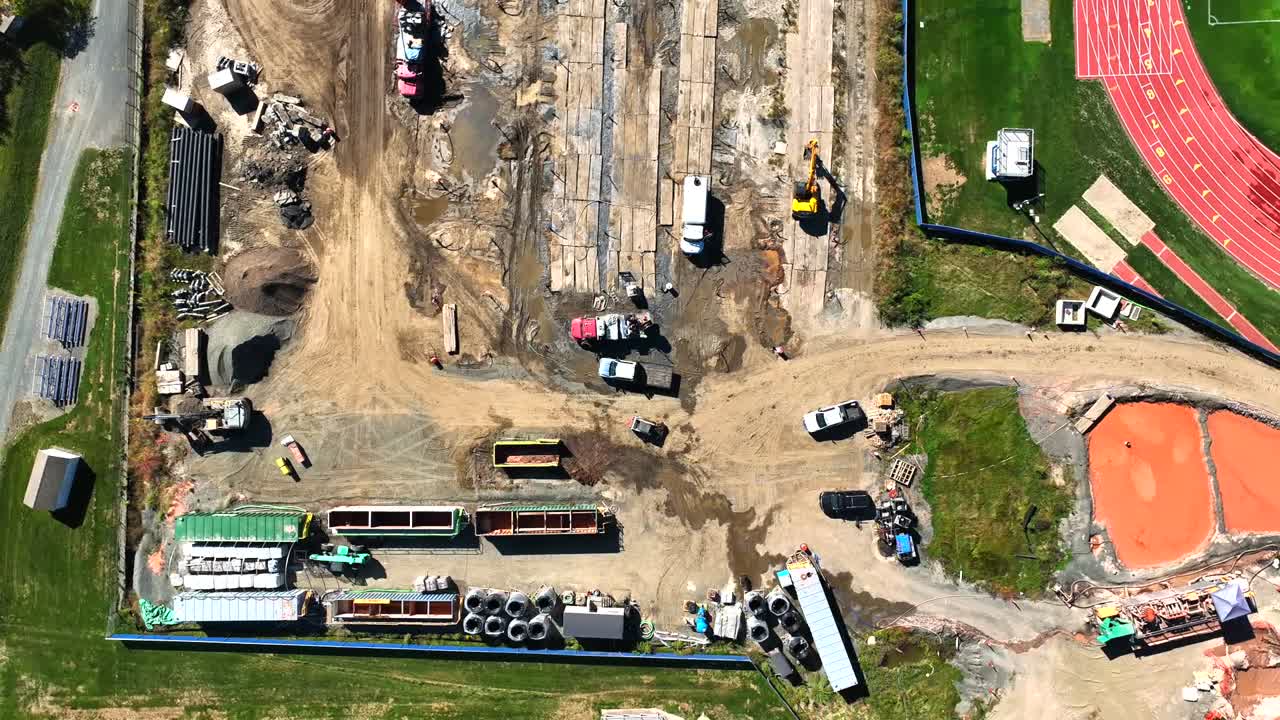 Smooth upward drone fly from a construction site with earthmoving equipment and vehicles