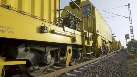 heavy yellow railway maintenance train on tracks with workers
