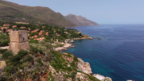 Backwards-Drone-Shot-Reveals-Scopello-Tower-at-Tonnara-di-Scopello,-Sicily,-Italy