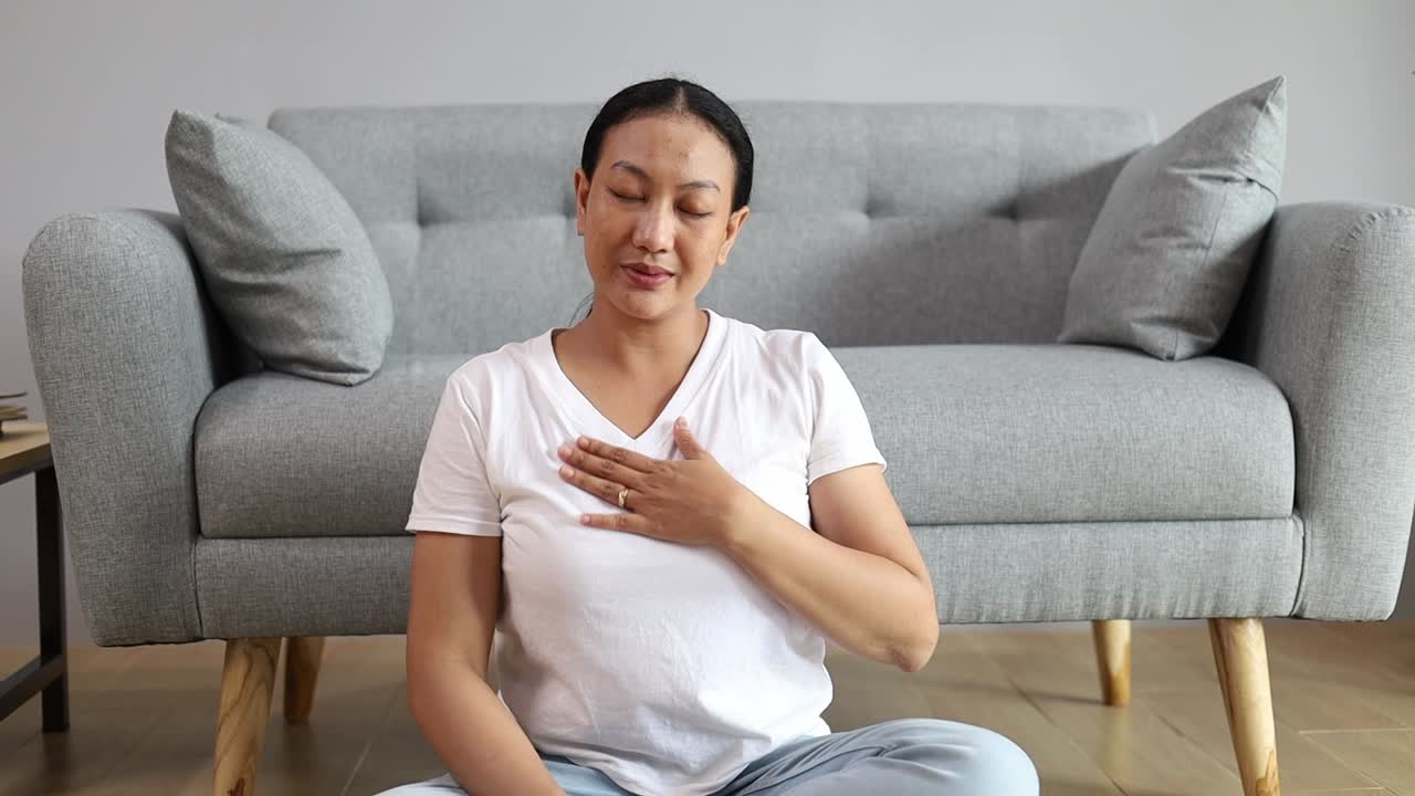 Donna asiatica seduta sul pavimento a casa con yoga, zen, calma e gestione dello stress per la cura della salute mentale