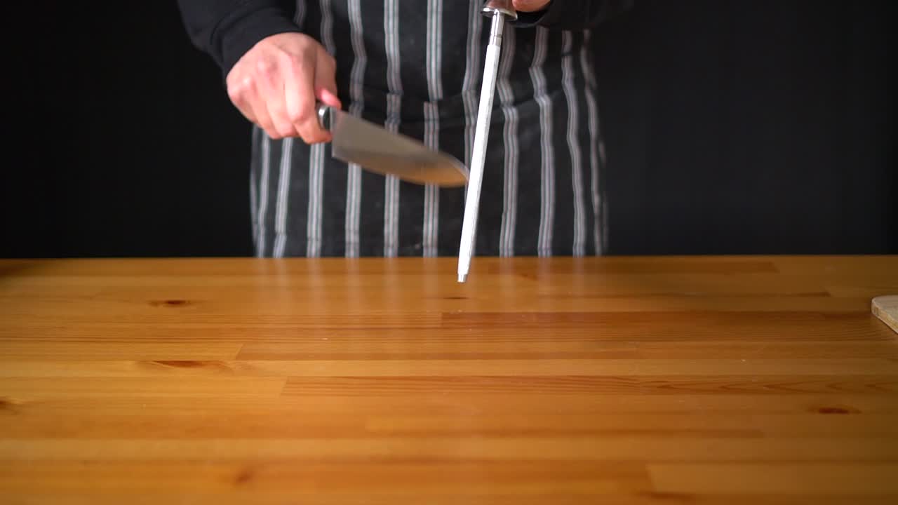 cámara lenta de un chef hombre usando varias técnicas para afilar un cuchillo con las manos, usando un cuchillo profesional y un acero afilado de diamantes