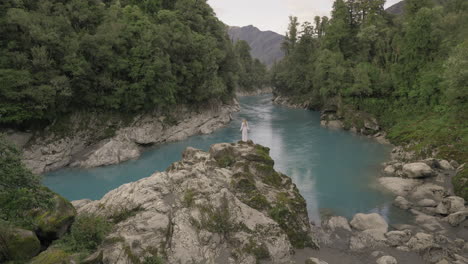 signora da favola in abito in piedi sulla roccia che domina il magico fiume blu, la gola di hokitika