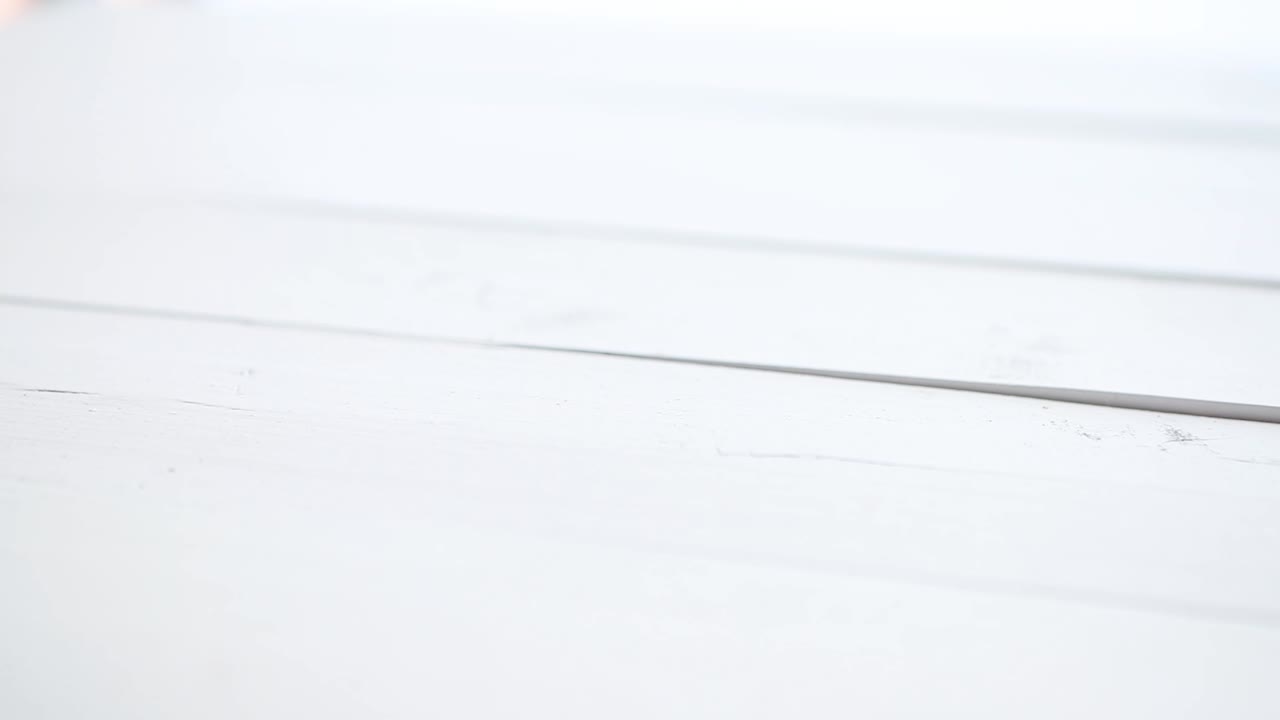 varios chiles rojos cayendo y rebotando en una mesa de madera blanca a cámara lenta