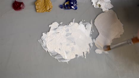 artist gently grabs yellow paint to mix with white creating lighter tan color