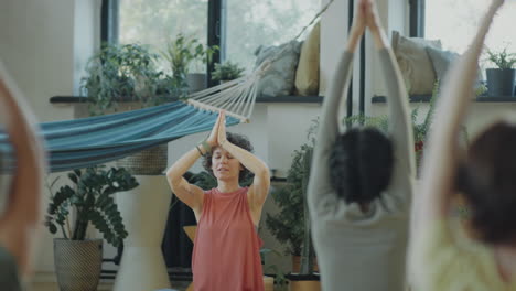 female yoga instructor leading group meditation