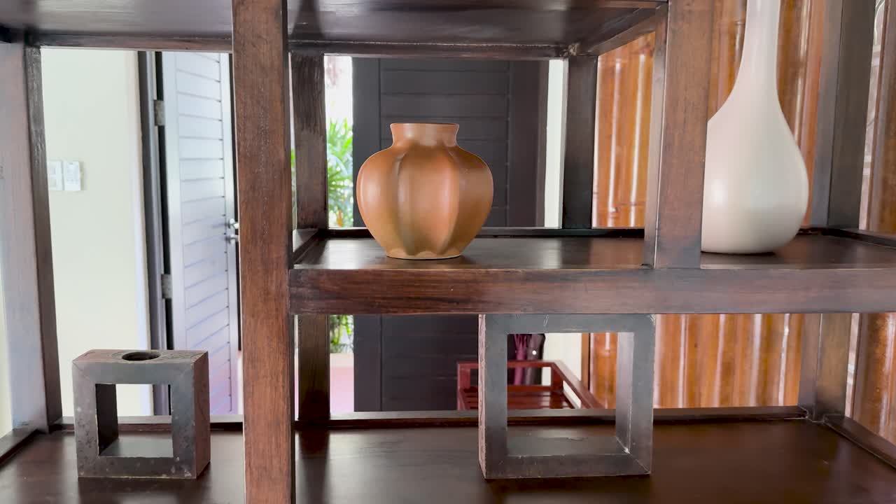 Camera slowly zooms on decorative wooden shelf with ceramic vases, natural daylight, indoor setting