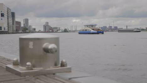 slow motion focus shot of a bollard at the ij in amsterdam with a ferry in the background