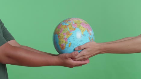 hands holding a globe on green background