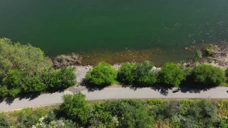 Top-down-aerial-shot-of-cyclists-riding-along-the-Spokane-River-Centennial-State-Park-Trail