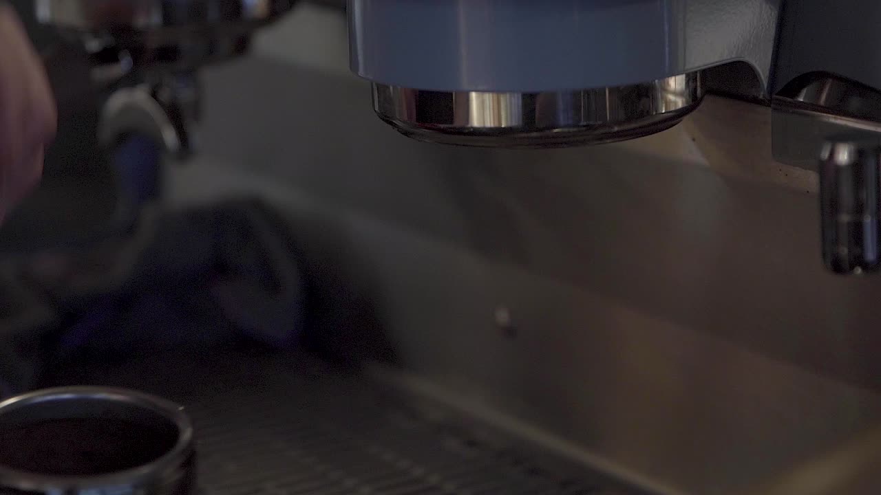 barista quita portafiltro con boquilla doble en cabeza de grupo de una máquina de café