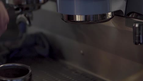 barista quita portafiltro con boquilla doble en cabeza de grupo de una máquina de café