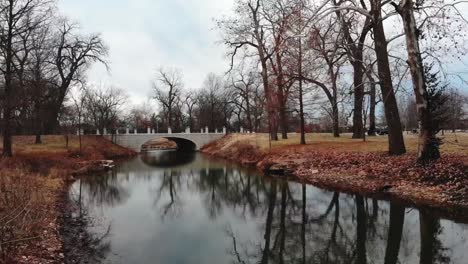 aerial drone footage of a low flight along a tranquil stream flowing through a city park