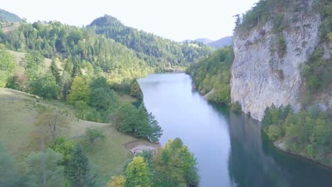 Breathtaking-cinematic-shot-of-small-lake-in-mountain-surrounded-by-the-green-forest