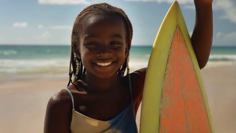 young girl smiling with a surfboard on a sunny beach