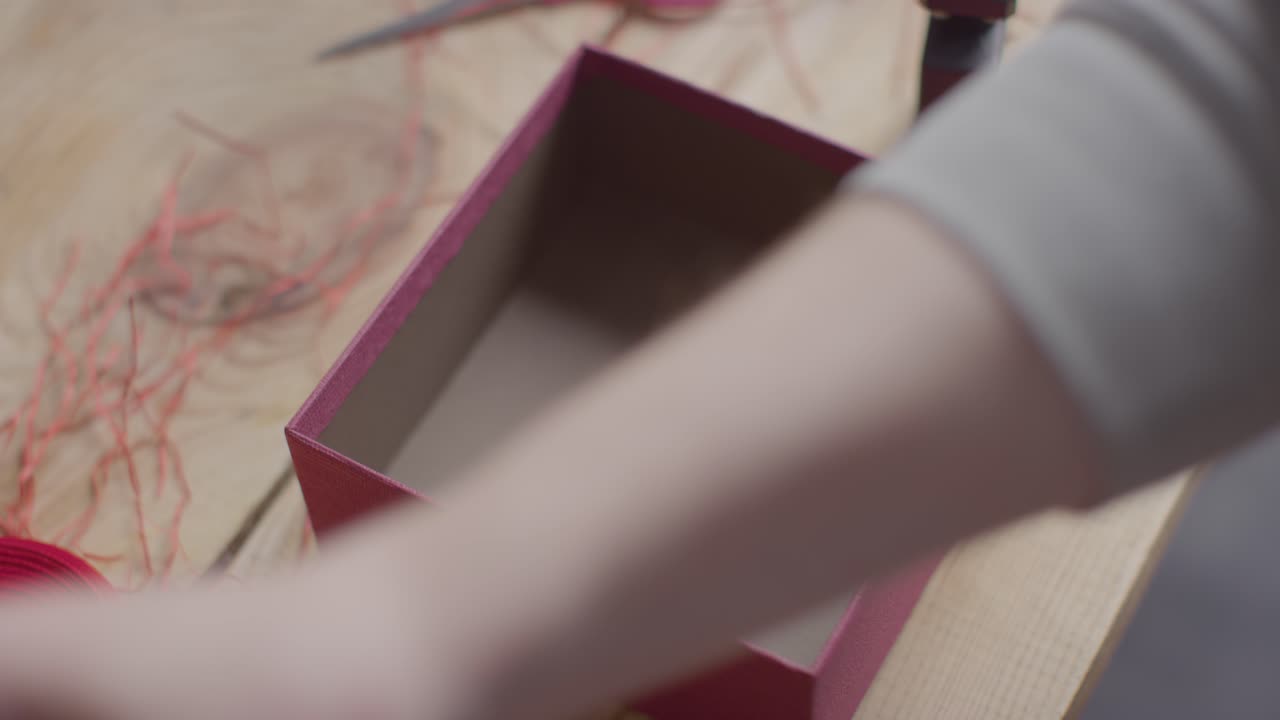 테이블 1에 있는 상자에 있는 향수의 낭만적인 발렌타인 선물을 포장하는 남자 선물의 클로즈업 샷