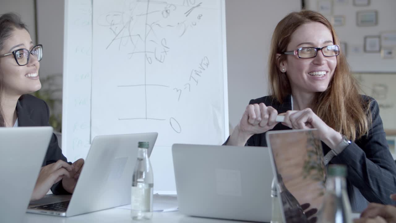 улыбающиеся деловые женщины обсуждают проект на рабочем месте