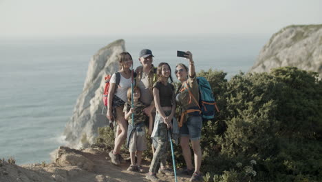 family of backpackers standing on cliff and taking selfie