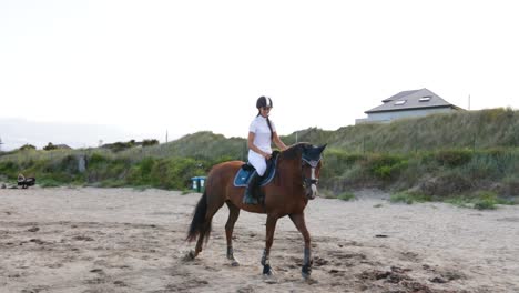 A-beautiful-girl-with-long-hair-rides-her-horse-on-the-beach-during-the-evening-in-Donabate,-Ireland