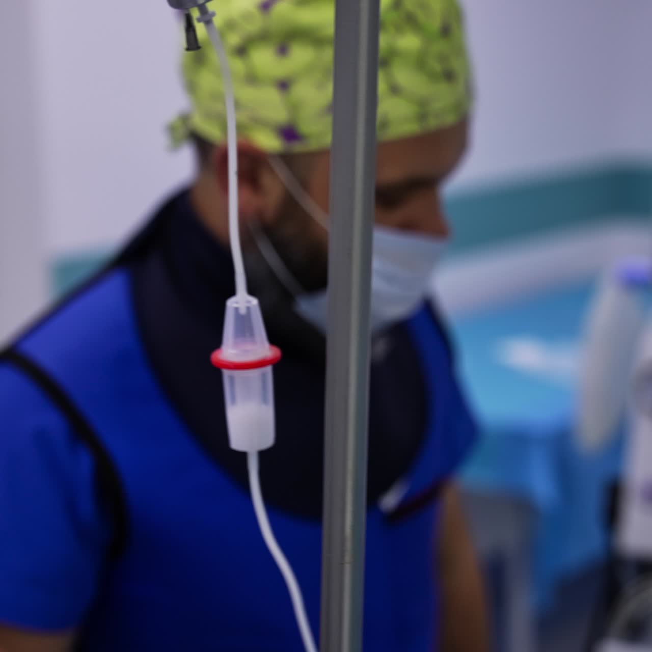 Male assistant is checking the injection drip during the surgery. Surgical equipment for operation close up. Blurred background