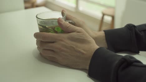 Man's-hands-hold-hot-herbal-tea-glass-in-a-cold-day