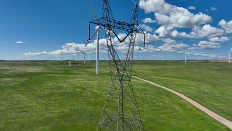 high voltage transmission power lines with wind turbine in background