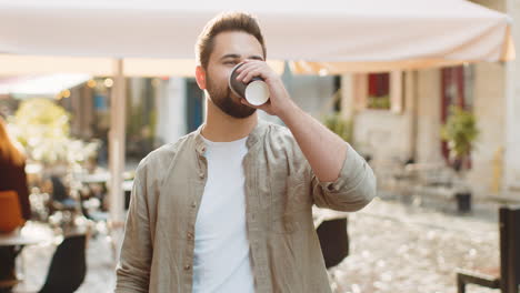 young man guy enjoying drinking morning coffee hot drink relaxing taking a break in city street